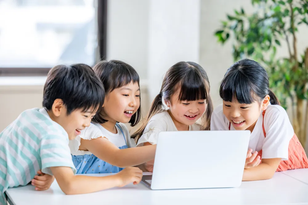 パソコンを囲んで学ぶ4人の子どもたち